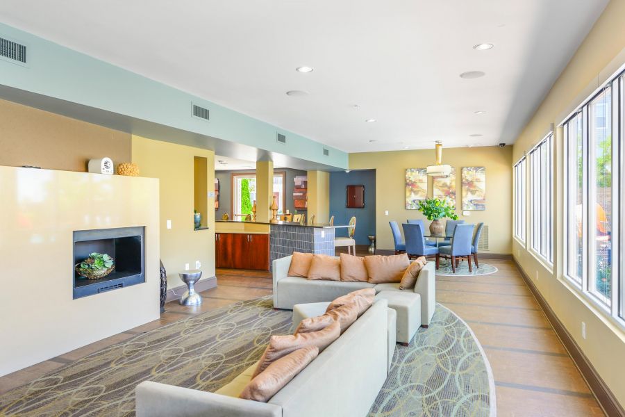 Modern lounge with beige sofas, a fireplace, dining table, and large windows letting in natural light.